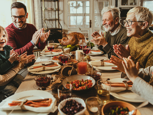 Multigenerational family enjoying Thanksgiving dinner together at home around a table with turkey, side dishes, wine, and holiday decorations, representing a well-planned family Thanksgiving where the host can relax, spend time with guests, and enjoy the celebration instead of managing the kitchen all day.