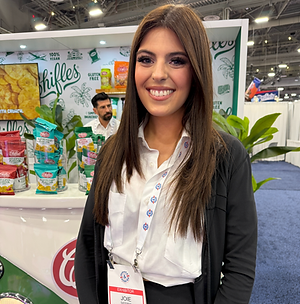 Smiling booth hostess supporting attendee engagement at a Las Vegas trade show exhibit. Positioned at a branded display, she welcomes visitors, answers initial questions, directs traffic, and helps create a positive first impression that encourages meaningful exhibitor interactions.
