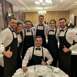 Las Vegas event floor captain photographed with a full service team during a formal banquet event. The floor captain supports servers on site, assigns responsibilities, monitors timing between courses, and keeps communication clear across the floor. This role is critical for Las Vegas corporate events, galas, weddings, and high-volume receptions where staff leadership, situational awareness, and operational consistency ensure guests receive organized, professional service from arrival to close.