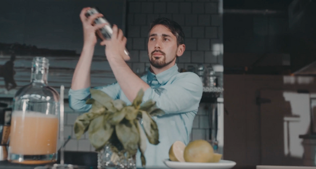 A professional Los Angeles event staff member preparing cocktails behind the bar at a private residential event. The image shows a trained bartender shaking a cocktail, surrounded by fresh ingredients and bar tools, representing high-quality event staff for residential events in Los Angeles. Ideal for clients looking to hire bartenders and servers for private home parties, intimate gatherings, or upscale celebrations in LA.
