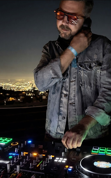 A corporate event DJ performs at a nighttime rooftop party overlooking the Los Angeles skyline while mixing music on professional DJ equipment. Corporate DJ in Los Angeles providing live entertainment for VIP receptions, networking events, luxury private parties, rooftop celebrations, company events, and exclusive nightlife experiences.