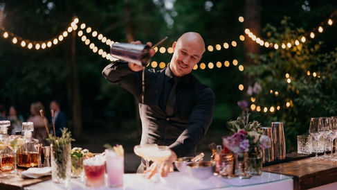 Professional event bartender in San Francisco shaking a signature cocktail at an outdoor venue, illustrating proper bar staffing ratios for a 100-guest event.