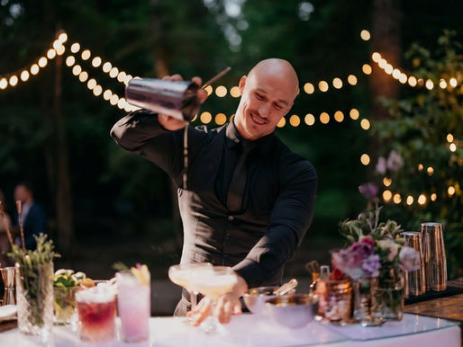 Professional event bartender in San Francisco shaking a signature cocktail at an outdoor venue, illustrating proper bar staffing ratios for a 100-guest event.