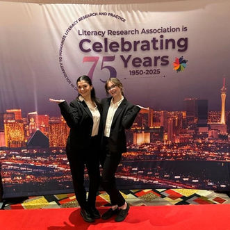 Registration attendants welcoming conference attendees at a Las Vegas association event, standing at a branded photo area near registration and guest services. Professional conference staff supporting attendee check-in, badge pickup, and event assistance during a large convention gathering.