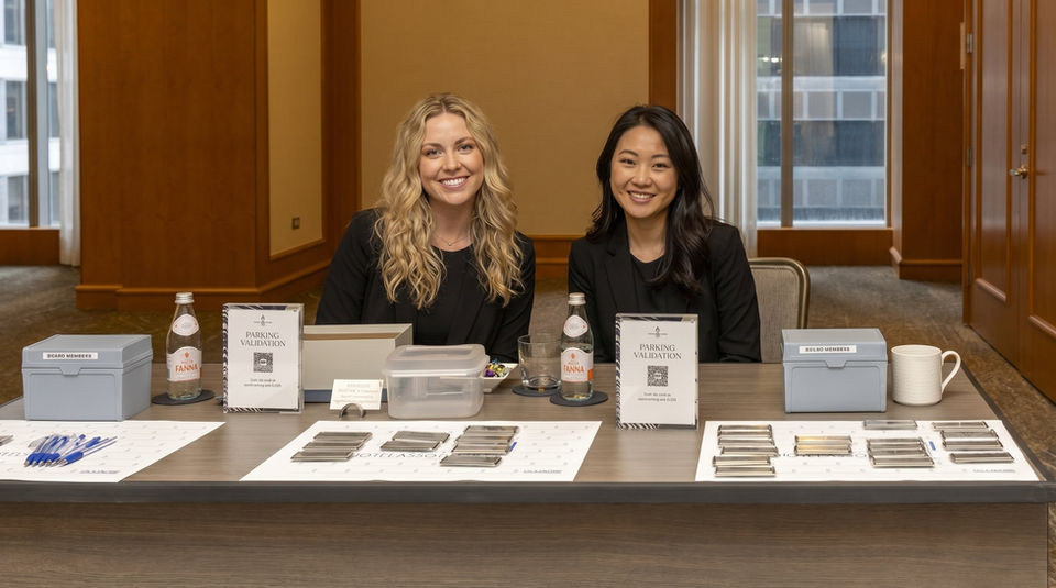 Conference guest registration staff in San Francisco managing attendee badges, executive summit check-in, and registration desk operations at a downtown corporate venue.
