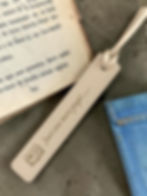 Cream bookmark next to some books engraved with Just One More Page...