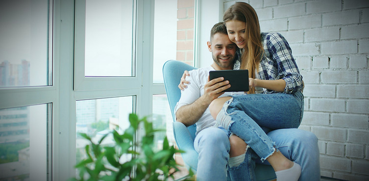 Young cheerful couple chatting and using