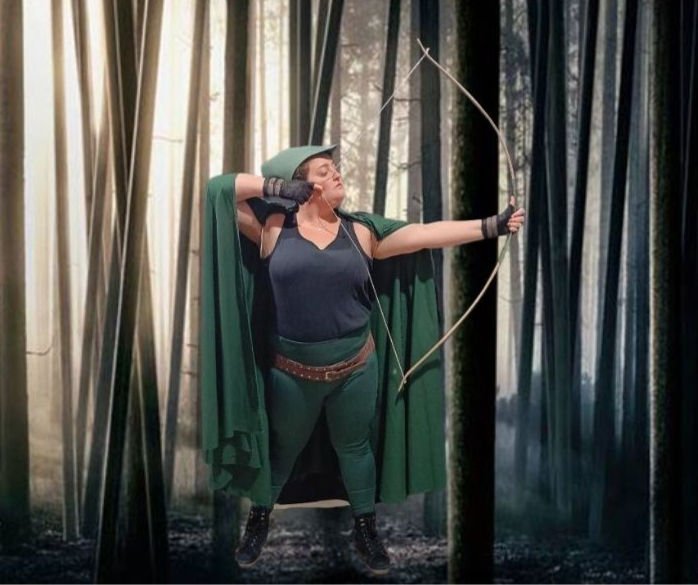 Robin Hood with bow and arrow drawn in front of a forest of trees