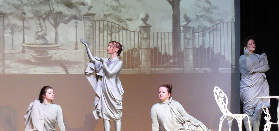 In the park, Neleus (Audrey Phillips) stands central, surrounded by statues played by Marie Hall, Kyra Charles, and Elizabeth Schoenborn.