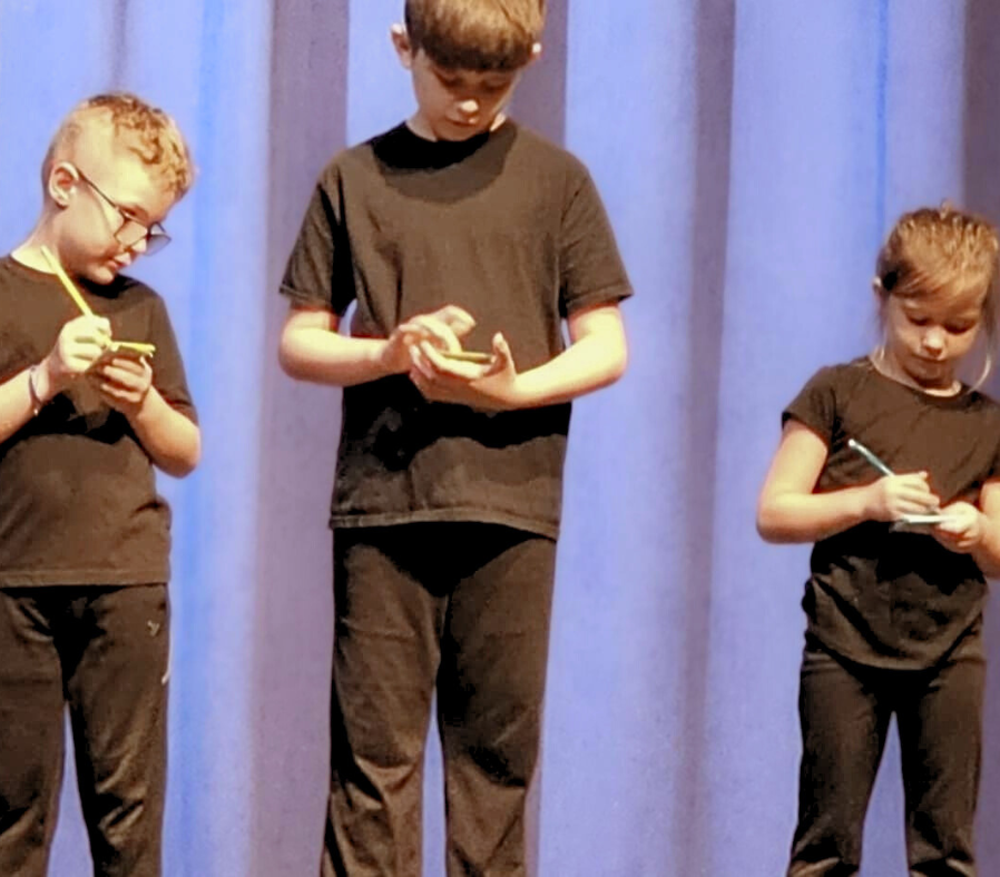 Three young actors writing on a pad of paper to vote for a story.