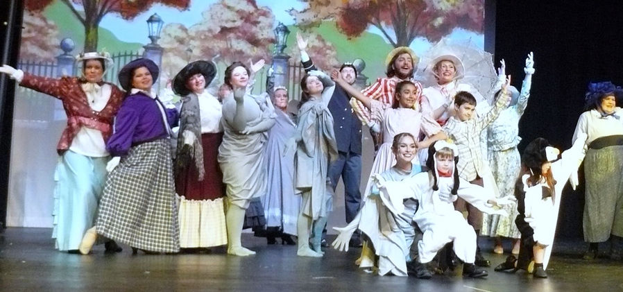 Mary, Bert, Michael, Jane, the statues, park-goers, and a group of penguins stand together with arms raised in celebration at the end of "Jolly Holiday."