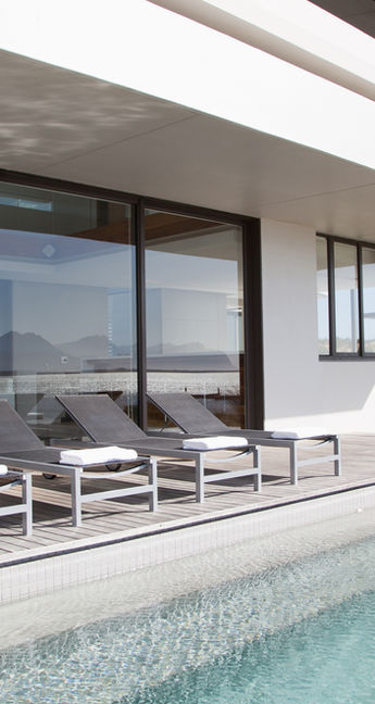 Exterior view of a newly constructed modern luxury house featuring glass walls and stone accents—custom home building services in Maryland