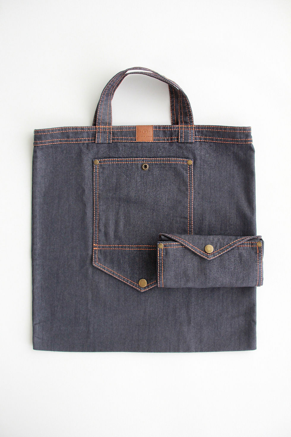 kompaktiškai sulankstytas ir susegtas spaude plono džinso pirkinių maišelis padėtas ant tokio pačio ištiesto maišelio