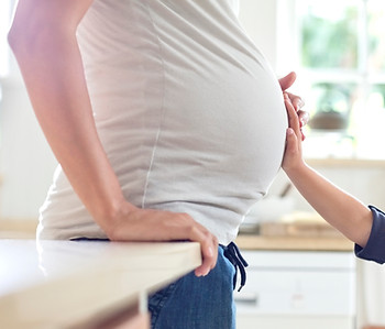 child holding pregnant woman's belly