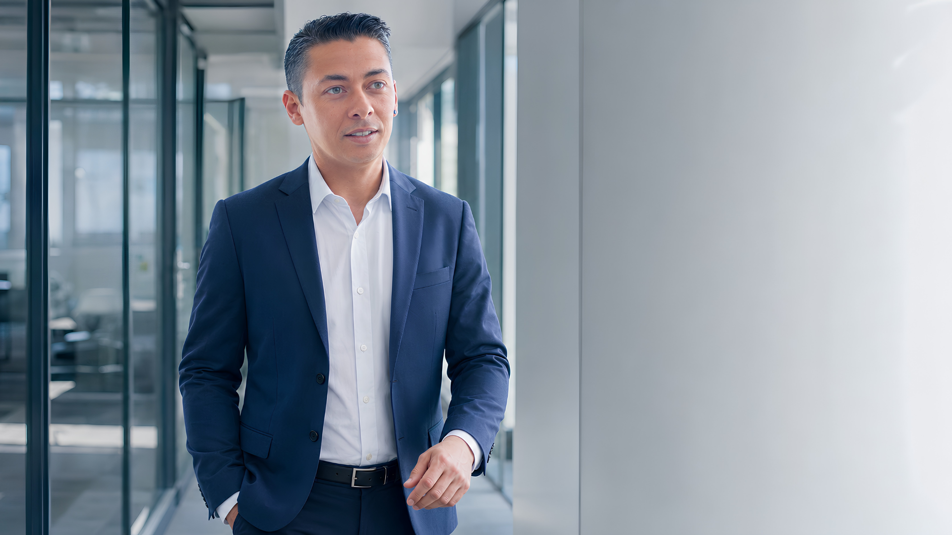 Soufiane Boudarraja walking through a modern office in a navy suit