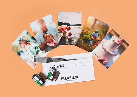 Fujifilm canisters arranged over a selection of printed photos on a n orange background