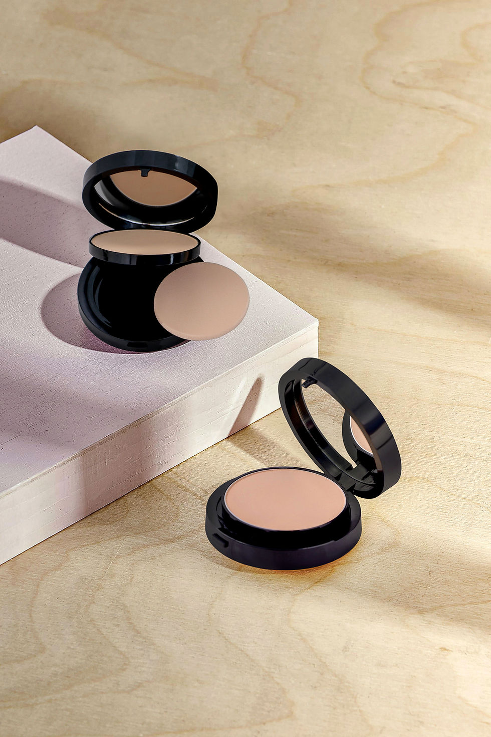 Two open makeup compacts, one with a puff