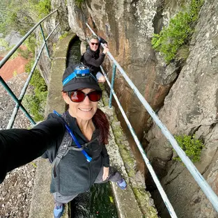 Woman standing on a narrow cliffside staircase during a hiking adventure.