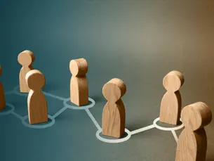 Wooden figures connected within a network, representing the interconnected development of people, businesses, and brands.