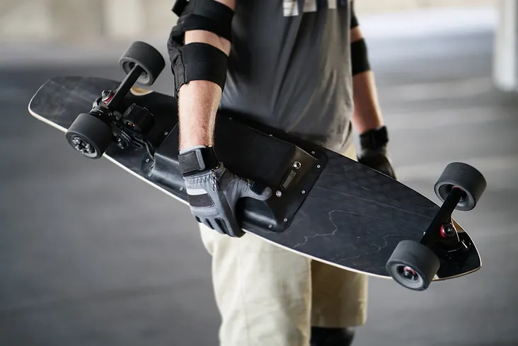 Person mit elektrischem Skateboard und Protektoren