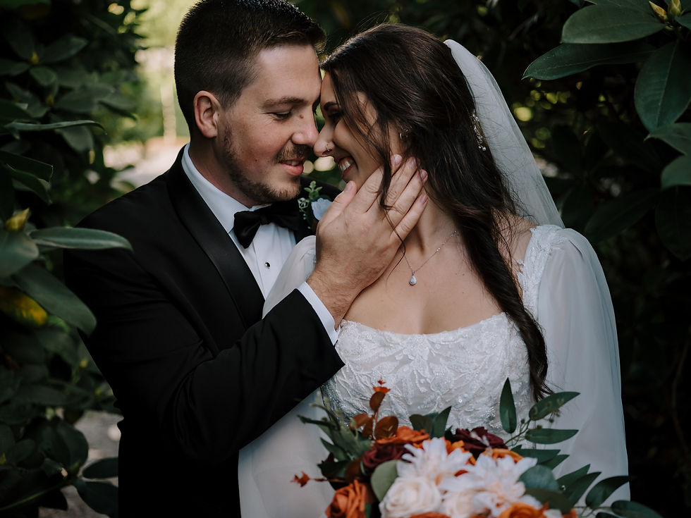 Close-Up of Intimate Moment: Bride and groom sharing a quiet, intimate moment in front of a forested backdrop.