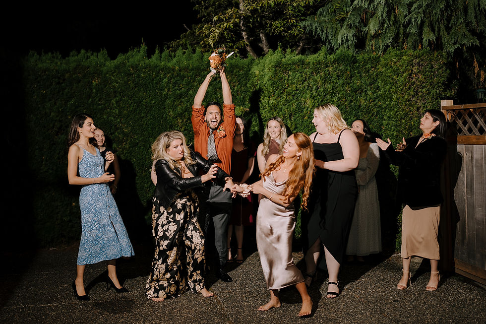 Bouquet Toss: One of the bride's men in mid-motion catching the bouquet in the air and screaming.