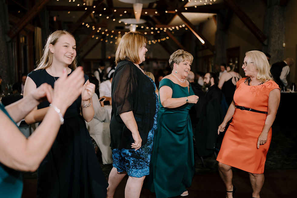 Guests Dancing: Group of wedding guests dancing energetically on the dance floor with colorful lights in the background.