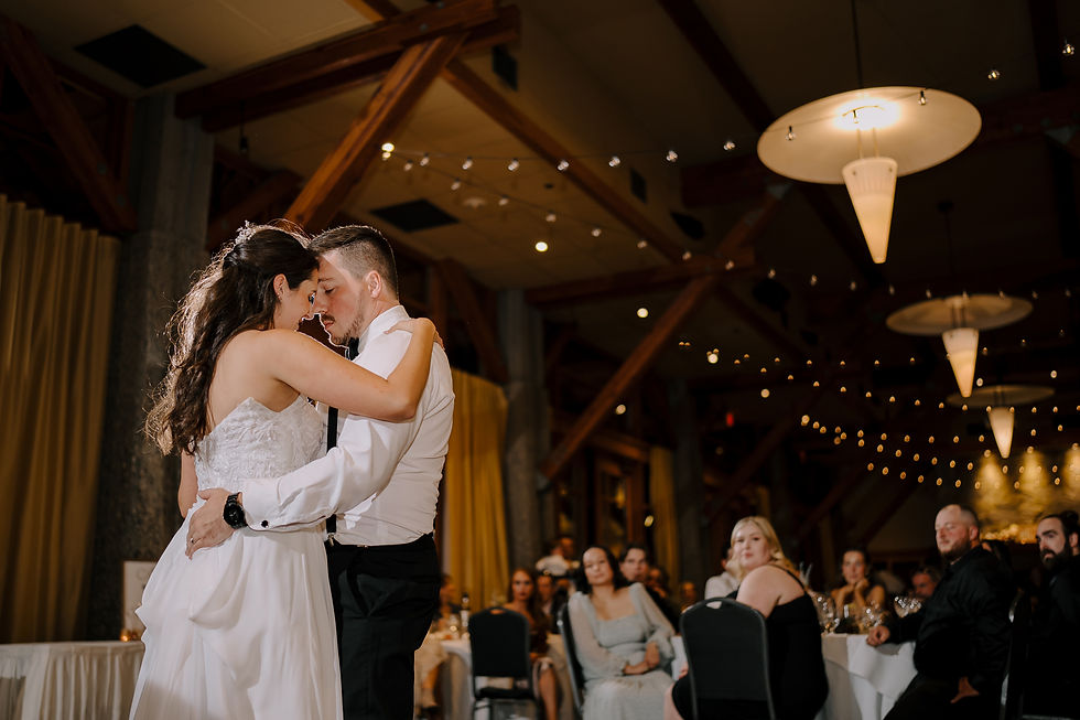 First Dance: Bride and groom sharing their first dance under soft, romantic lighting, with guests watching in the background.
