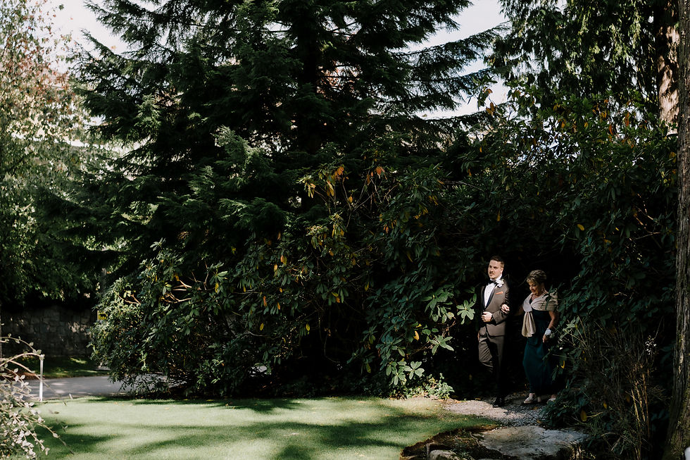 Groom and mother of the groom walking towards the ceremony. Dark and moody image to fit our style and brand.