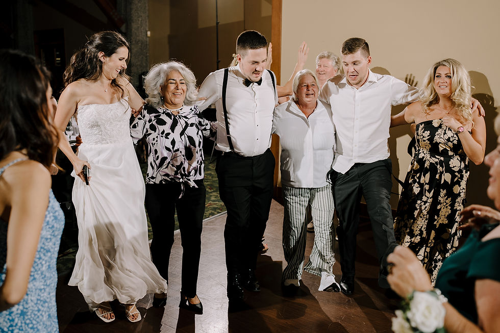 Guests Dancing: Group of wedding guests dancing energetically on the dance floor with colorful lights in the background.