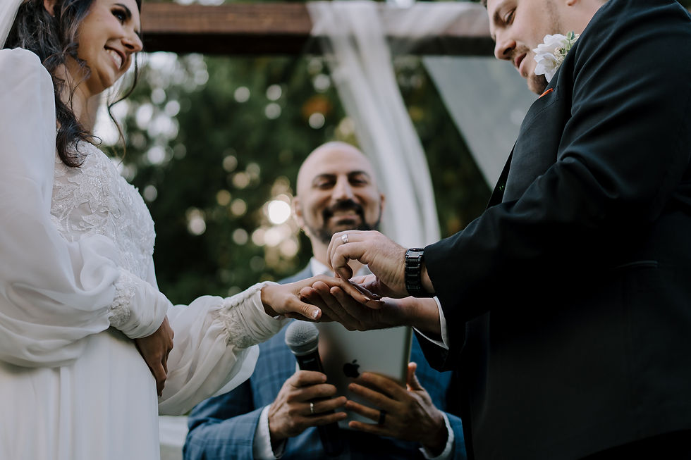 Ceremony image: Groom and bride exchanging rings from a lower angle.