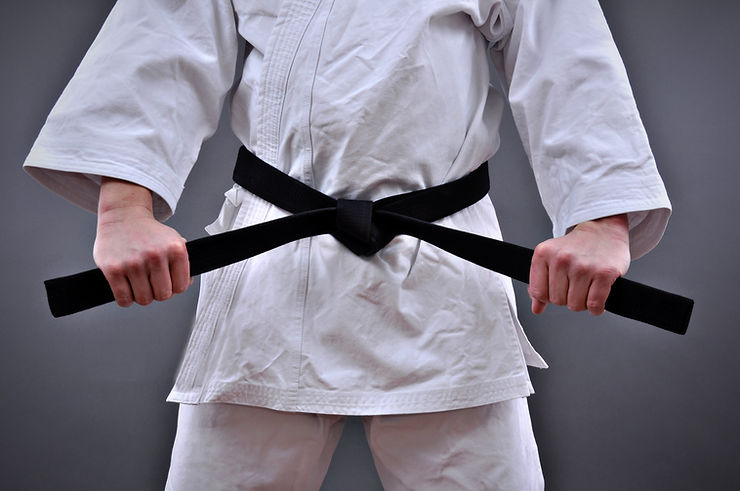 Person in martial arts attire pulling on his black belt