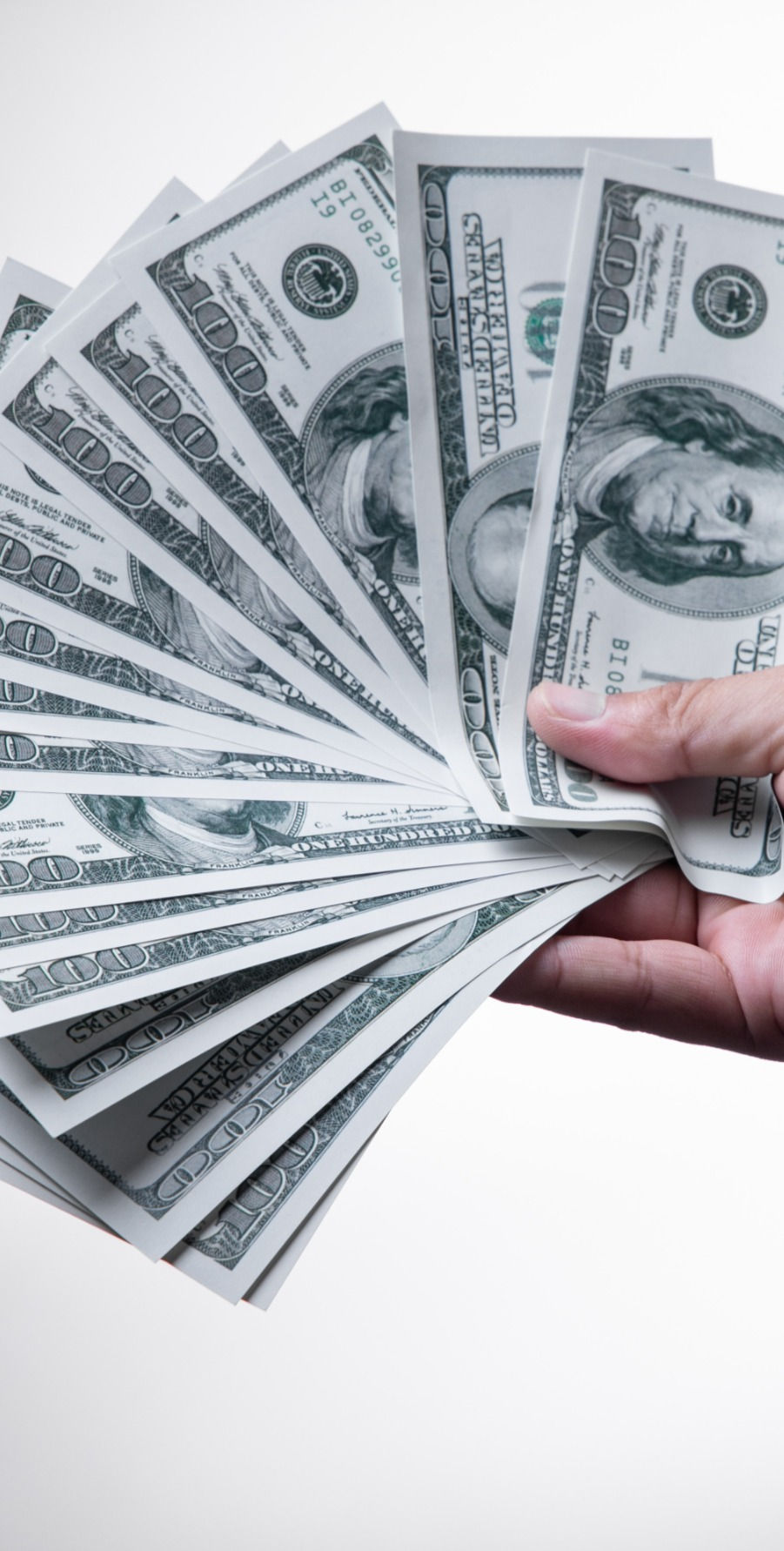 A hand holding one hundred dollar bills