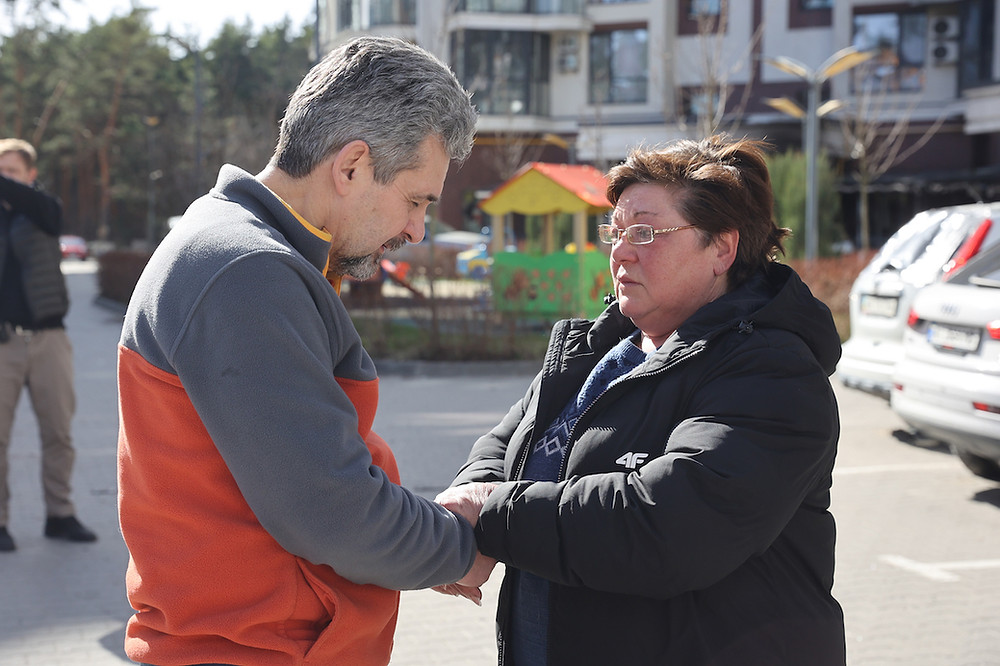 Sergiy prays with a woman in Kyiv