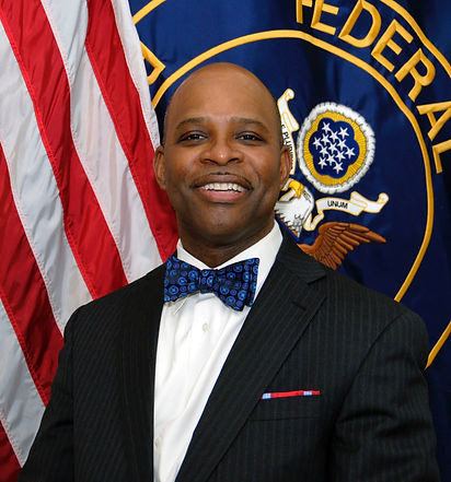 Patrick smiling in professional photoin front of flag