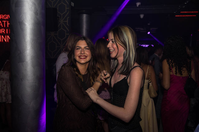 Two people smiling and dancing in a dimly lit venue.