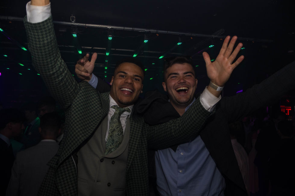 Two people smiling and raising hands at an event.