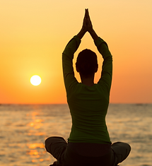 Uma mulher meditando ao por do sol