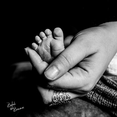 Main de mamana vec le pied de bébé au studio en shooting naissance à Bordeaux