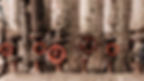 Industrial pipes with red valve wheels against a worn brick wall. Pipes are wrapped in various materials, creating a rustic, gritty mood.
