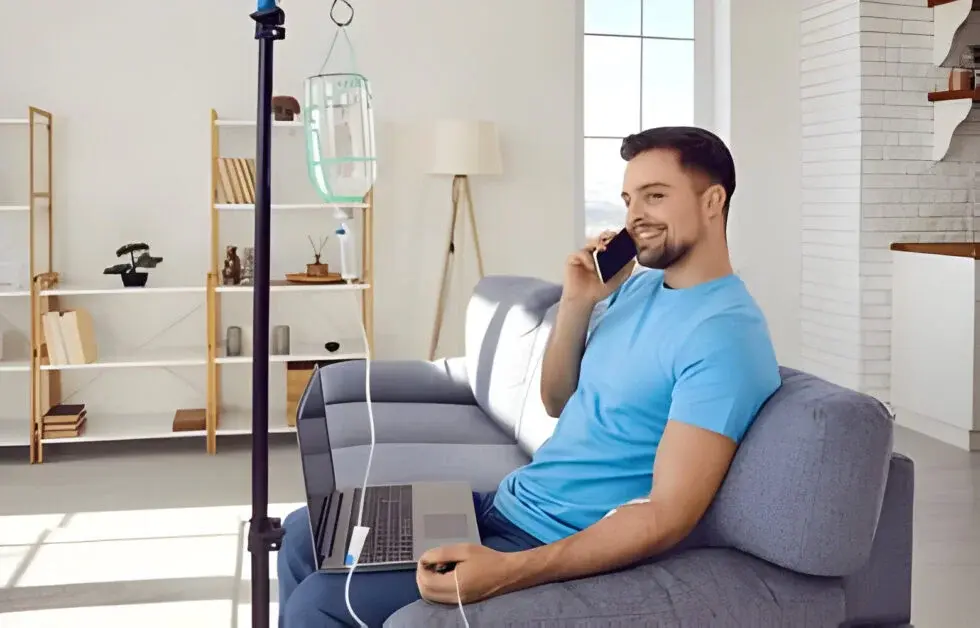 A man getting Hangover IV Drip at his home while he is working and answering the phone