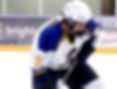 Ice hockey player in blue and white jersey number 71 skates crouched on the rink, focused and gripping his stick.