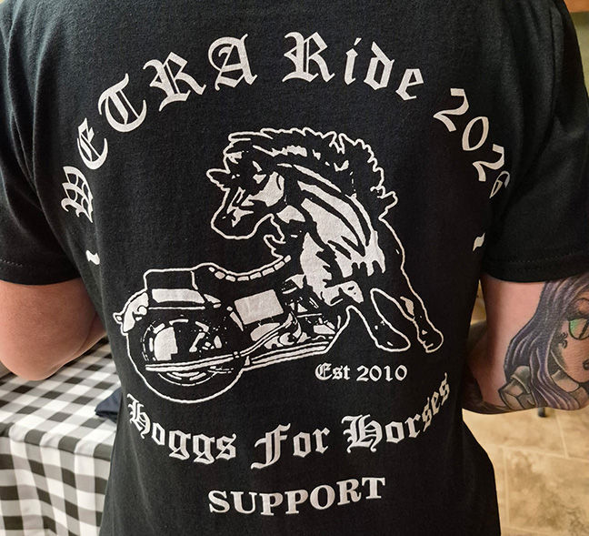 Back of person in black WETKRA Ride 2020 T-shirt with rearing horse on motorcycle; Hogs for Horses SUPPORT, Est 2010.