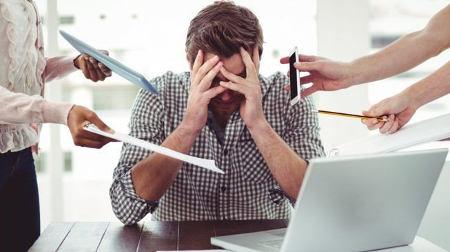Un trabajador estresado en su escritorio, sumergido de trabajo y pedidos