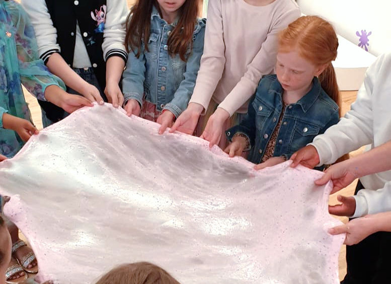 children stretching giant slime together at a slime party