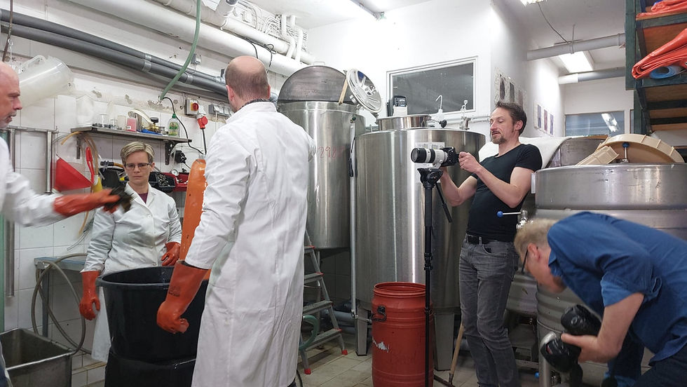 Dreharbeiten in einer Produktionsstätte für Meeresalgenkosmetik: Das Team filmt den Herstellungsprozess inmitten industrieller Tanks und Ausrüstungen.