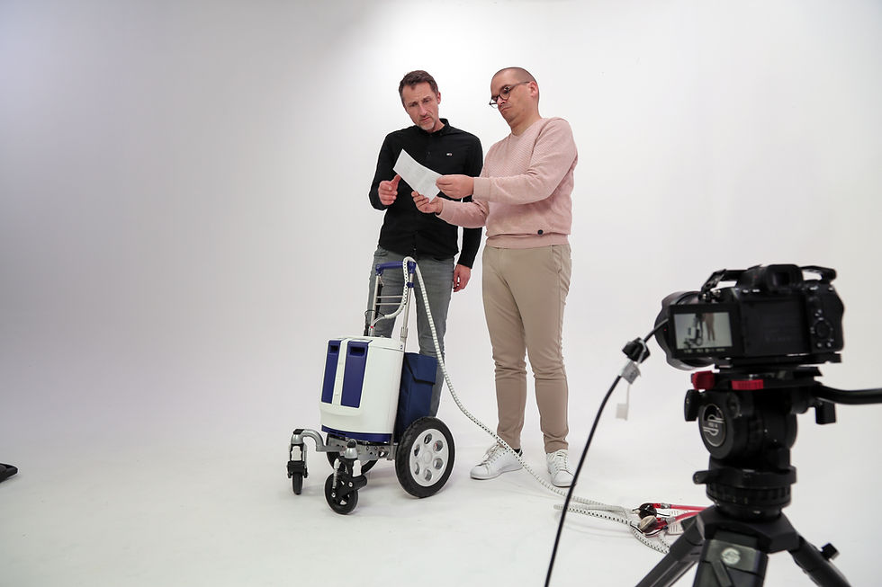 Produktionsbesprechung bei den Dreharbeiten für einen Film über Medizintechnik: Zwei Personen prüfen das Drehbuch vor der Kamera, während ein medizinisches Gerät bereitsteht.