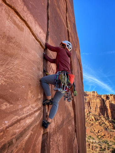 Guided Climbing Moab: guide leading a Crack climb to hang a towrope. Learn the basics of climbing, moving your body on rock, belaying and keeping another climber safe, and lowering from the top. Our AMGA certified guide will keep you safe and tailor the instruction to expand on what you know!