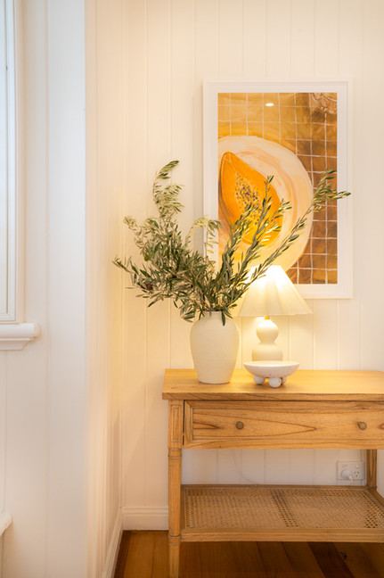 an interior design moment side table in a bedroom with a rpint and potplant on a table with olive flowers by Haus of Gray Interior Design