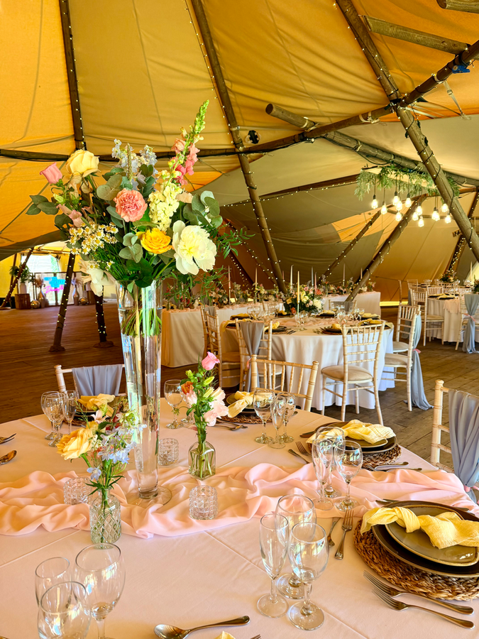 Tall wedding table centrepiece with seasonal florals in a vase, surrounded by bud vases and candles on a reception table for Oxfordshire wedding.